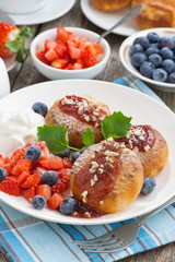 sweet cheese pancakes with berries and cream on a plate, closeup