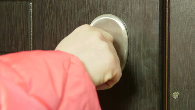 Female hand with key locking or unlocking the front door