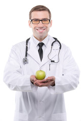 Portrait of young male doctor holding green apple. Isolated on w