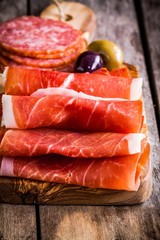 thin slices of prosciutto with salami on a cutting board