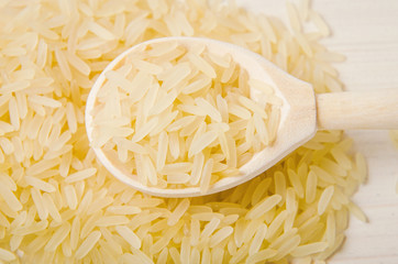 golden rice spilled on a spoon wooden table