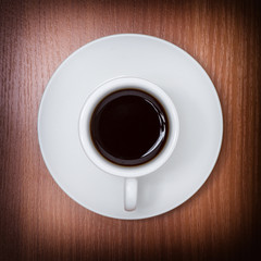 Coffee served on white cup, on wooden table. Upper view with woo