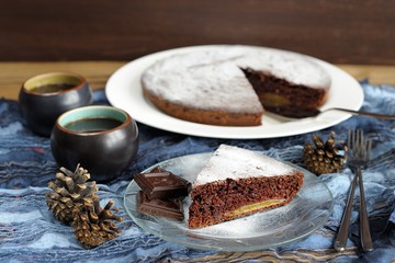 Chocolate cake with pine cones and black tea on blue cloth