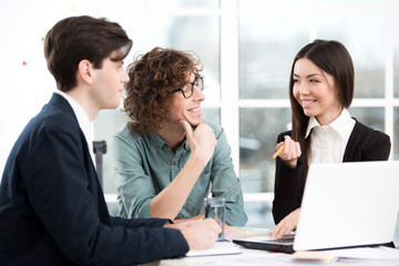 Asian businesswoman and two businessmen working with laptop in