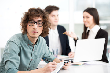 Obraz premium Young businessman using notebook with his business team on