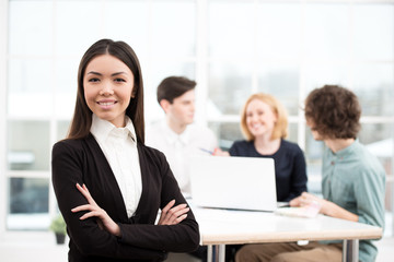 Businesswoman looking at camera with her business team on