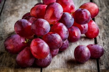 branch of ripe organic grapes on wooden background