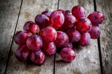 branch of ripe organic grapes on wooden background