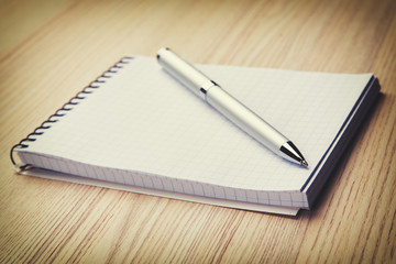 Blank notepad with pen on office wooden table