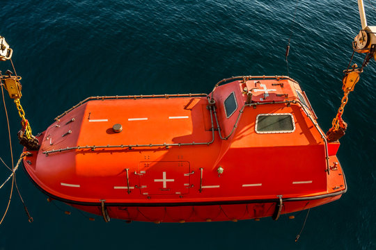 Lowered orange lifeboat with a sea background