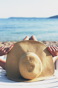 Tropical, woman sunbathing on the beach with hat