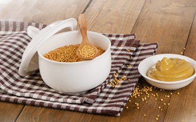 Mustard seeds and sauce on a wooden background