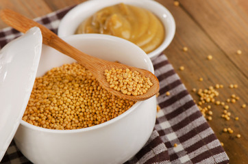 Mustard seeds and sauce on  wooden background