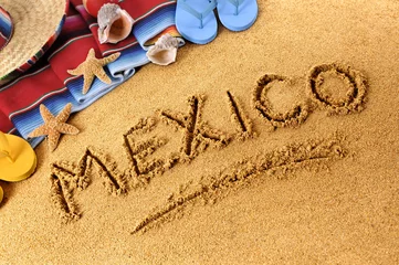 Washable wall murals Mexico Mexico beach writing word written in sand with traditional rug or blanket and sombrero photo