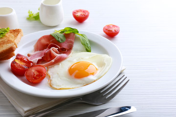 Bacon and eggs on color wooden table background