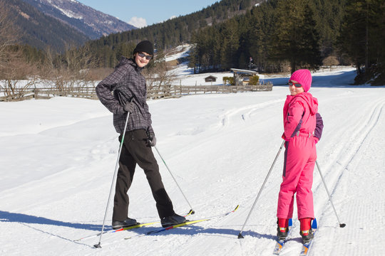 Teenage boy and girl enjoying cross country skiing  and looking at camera,  valley in Stubai - Austrian Alps. 
