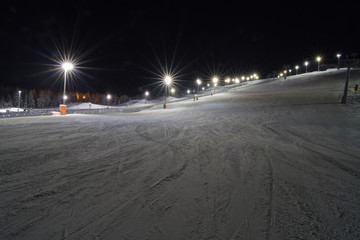 Fototapeta na wymiar Night skiing in Levi, Finland. Groomed ski slopes illuminated at night