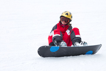 Fototapeta na wymiar Little girl on a snowboard sitting and resting on snow