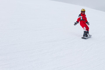 Fototapeta na wymiar One little girl snowboarding, riding down on ski slope