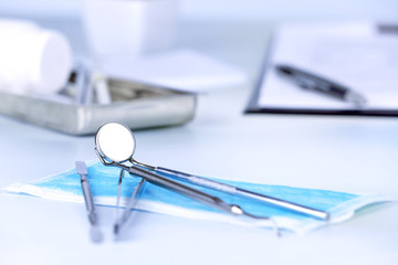 Dentist tools with medical mask on table close up