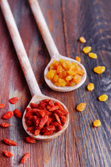 Raisins and Goji in spoons on rustic wooden table background