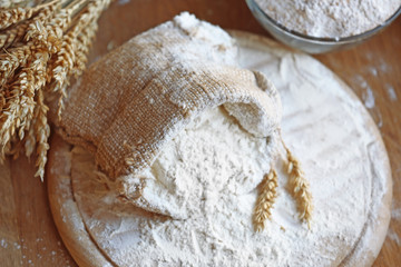Flour in burlap bag on cutting board and wooden table