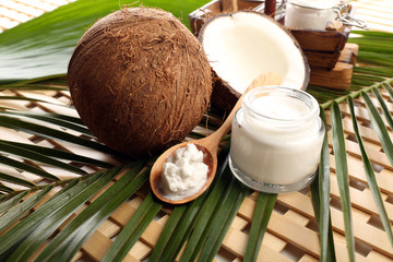 Coconut with leaf and cosmetic cream in jar on wooden