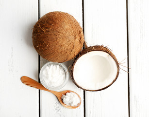 Coconut with coconut oil in jar on wooden background