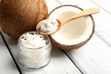 Coconut with coconut oil in jar on wooden background