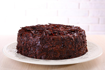 Tasty chocolate cake on table on brick wall background