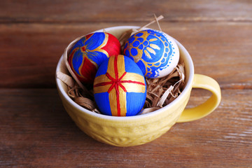 Easter eggs in mug on wooden background