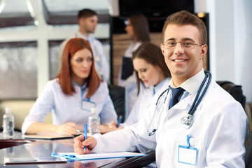 Fototapeta premium Attractive male doctor with team in conference room