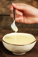 Bowl with condensed milk and spoon on table close up