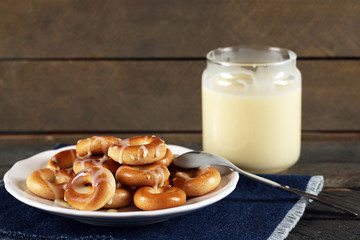 Bagels on plate with jar of condensed milk on wooden background