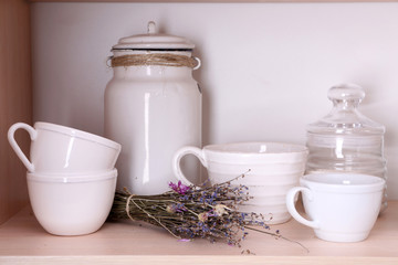 Kitchen utensils and tableware on wooden shelf