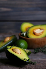 Sliced avocado with herb in bowl on wooden background