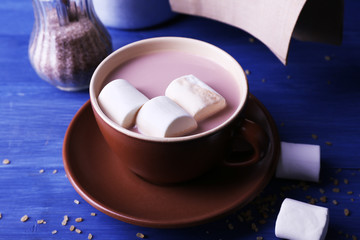 Fototapeta na wymiar Cup of cocoa with marshmallows on color wooden background