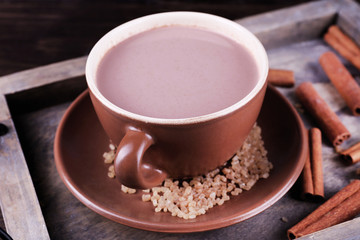 Cup of cocoa with sugar and cinnamon on wooden tray, closeup