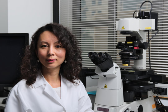 Asian Female Scientist Sitting At Microscope