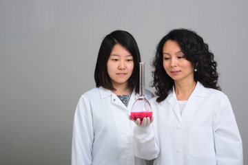 Two asian female scientists examining volumetric flask