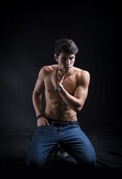 Handsome muscular shirtless young man kneeling down on the floor