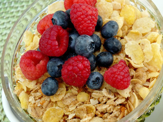 A bowl of breakfast cereal topped with blueberries and raspberri
