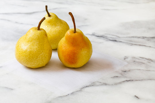 Yellow pears on white marble kitchen counter, with white netting