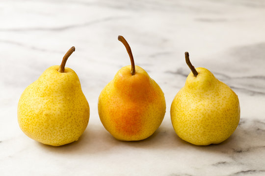 Yellow pears in a row on white marble kitchen counter