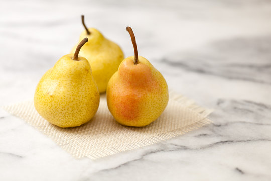 Yellow pears on white marble counter with burlap square