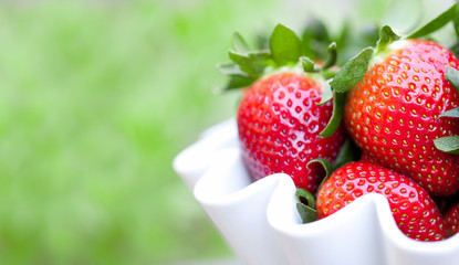 Strawberries in a white bowl close up with copy space