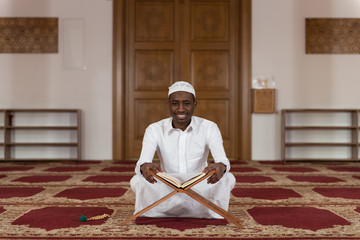 Young African Muslim Guy Reading The Koran