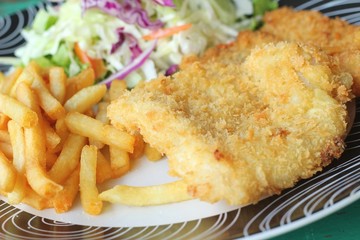 Steaks, french fries with vegetables salad on a plate.