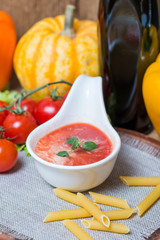 Tomato sauce in a white sauce boat with fresh ingredients