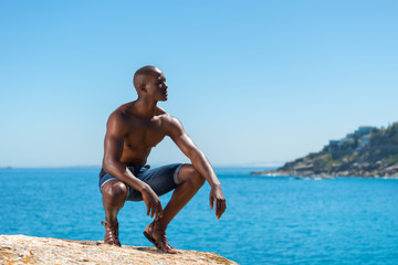 Fototapeta na wymiar Topless African black man crouching with short jeans